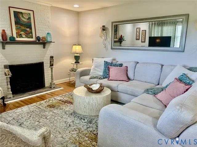 a living room with couches a fireplace and kitchen view