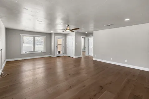 an empty room with wooden floor and windows
