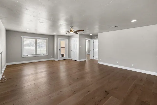 an empty room with wooden floor and windows