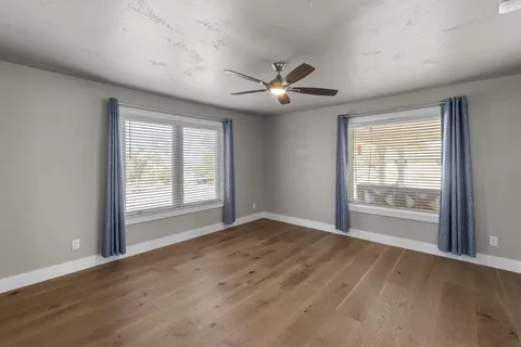 a view of an empty room with a window and wooden floor