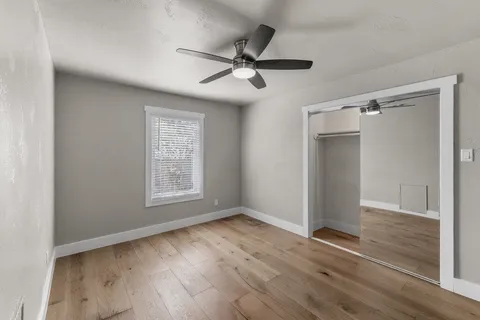 a view of an empty room with wooden floor and a window