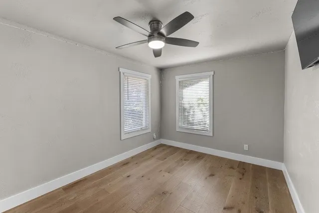 a view of an empty room with wooden floor and a window
