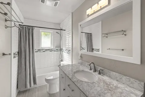 a bathroom with a granite countertop sink toilet a mirror and shower