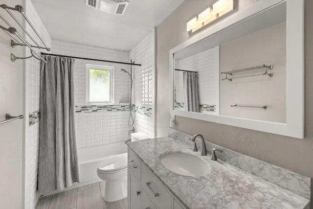 a bathroom with a granite countertop sink toilet a mirror and shower