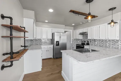 a kitchen with stainless steel appliances granite countertop a sink refrigerator and cabinets