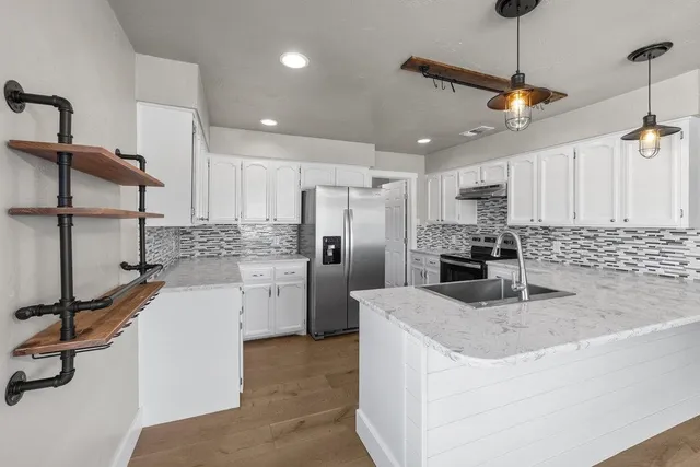 a kitchen with stainless steel appliances granite countertop a sink refrigerator and cabinets