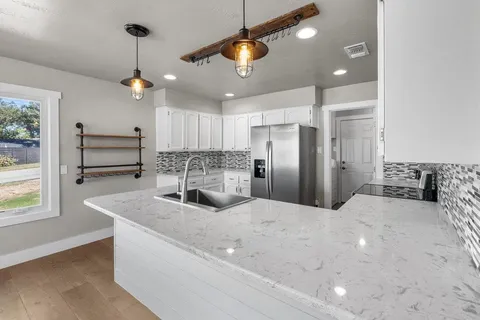 a kitchen with stainless steel appliances kitchen island granite countertop a sink a refrigerator and a stove