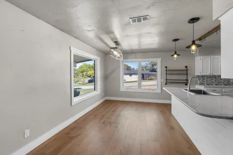an empty room with windows and open kitchen view