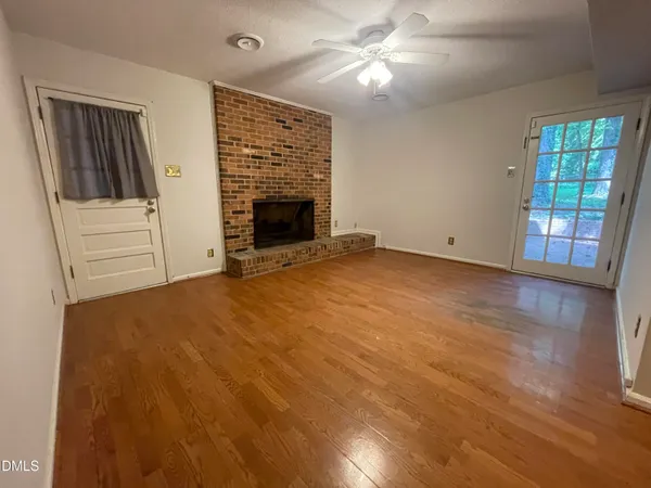 an empty room with windows and fireplace