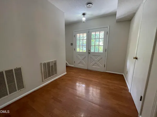 an empty room with wooden floor and windows