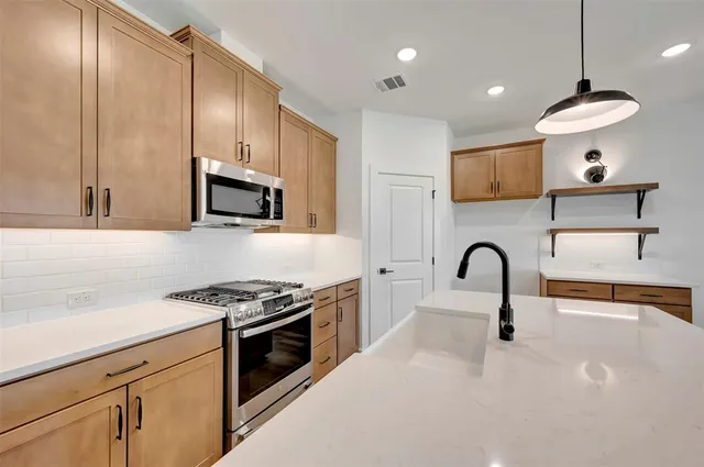 a kitchen with stainless steel appliances a stove a sink a microwave and cabinets
