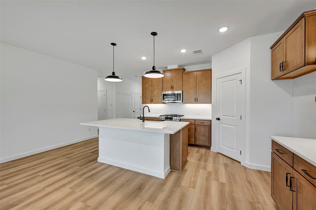 524 Brookside Drive Van Alstyne, TX 75495 - Photo 9 of 32 a kitchen with a sink wooden floor and white cabinets