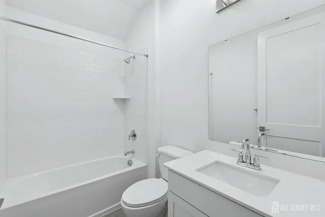 a bathroom with a bathtub shower sink vanity mirror and toilet