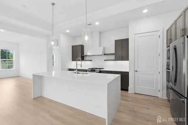 a kitchen with stainless steel appliances a refrigerator a sink dishwasher a stove and white cabinets with wooden floor