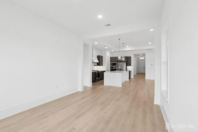 a view of a kitchen with kitchen island wooden floor center island and stainless steel appliances