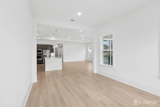 a view of an empty room with kitchen and window