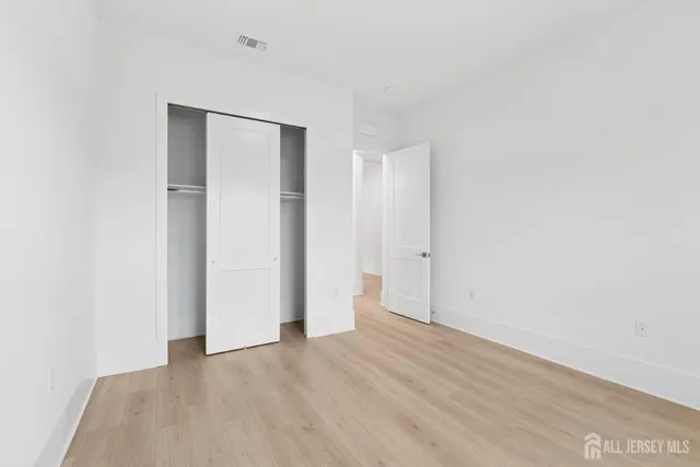 a view of an empty room with wooden floor and closet