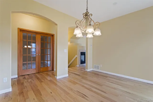 a view of a livingroom with a chandelier fan front door and wooden floor