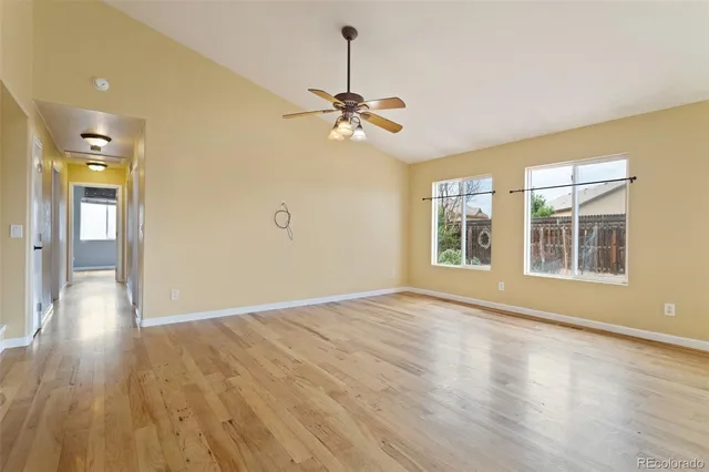 a view of an empty room with window and wooden floor