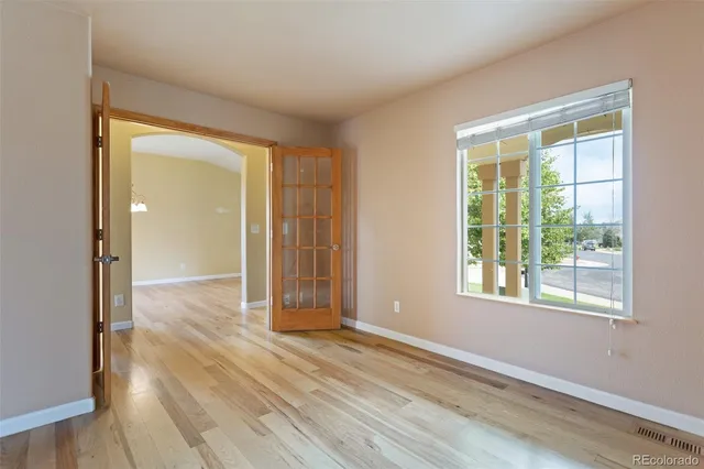 an empty room with wooden floor and windows
