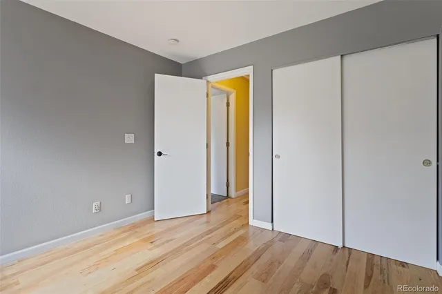 a view of an empty room with wooden floor and closet