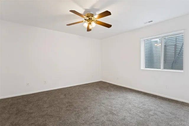 an empty room with window and ceiling fan
