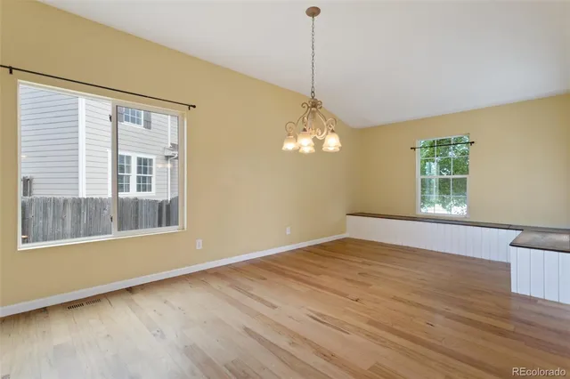 a view of an empty room with a window and wooden floor