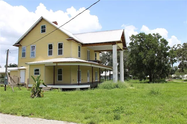 a view of a white house with a big yard and large trees