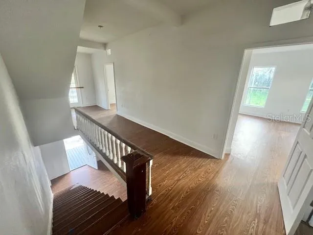 a view of a hallway with wooden floor and stairs
