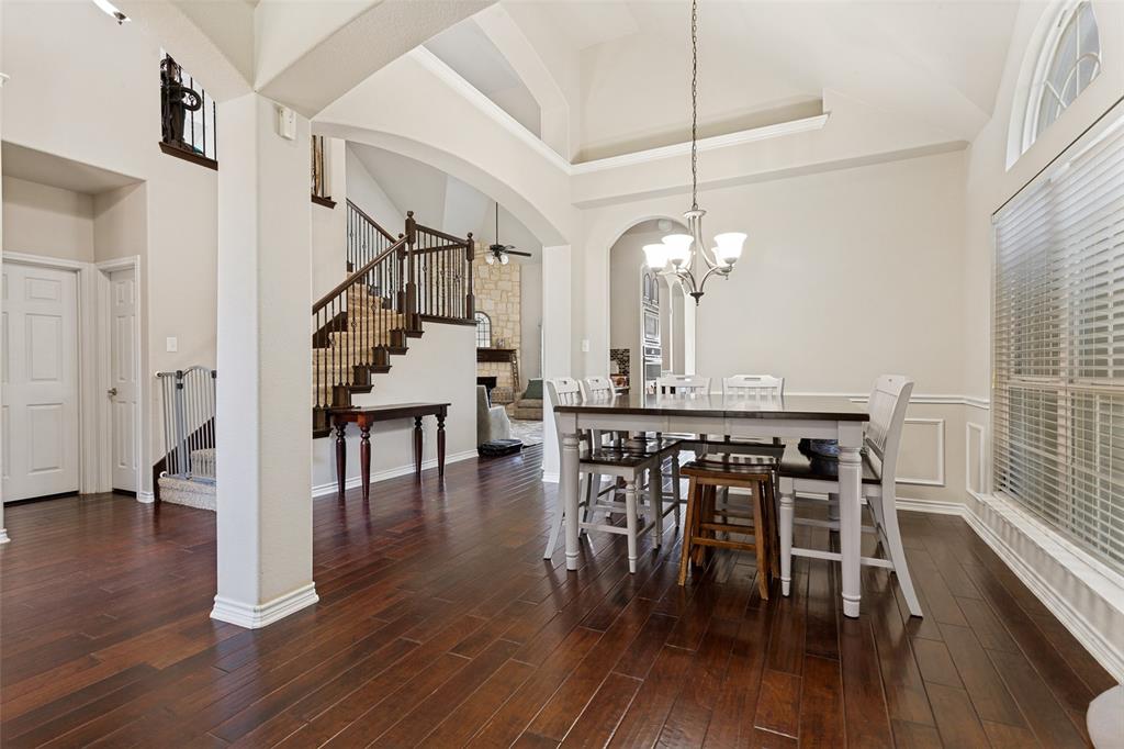 4117 Autumn Path Road Denton, TX 76208 - Photo 3 of 14 Spacious dining area featuring dark wood-finish flooring, a contemporary chandelier, and a large window with an arched transom