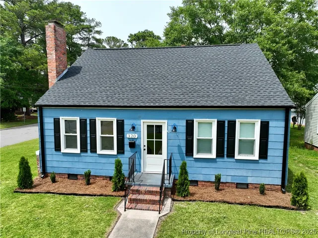 a view of brick house with a yard