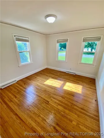 a view of empty room with window and wooden floor