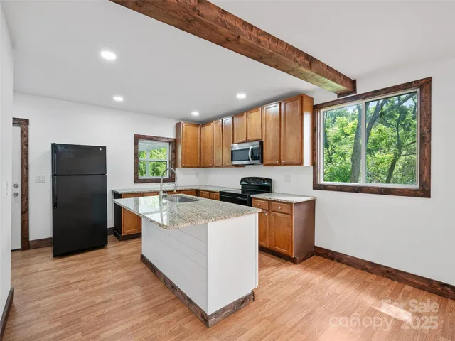 a kitchen with stainless steel appliances granite countertop a refrigerator a sink dishwasher a stove and a refrigerator with wooden floor