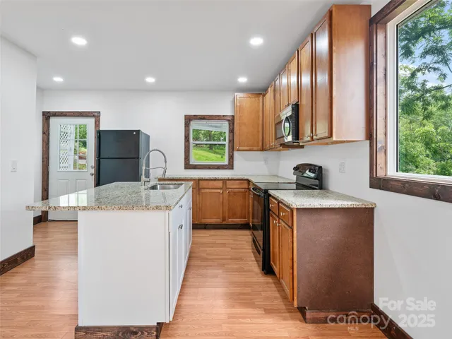 a kitchen with stainless steel appliances granite countertop a stove a sink and a refrigerator