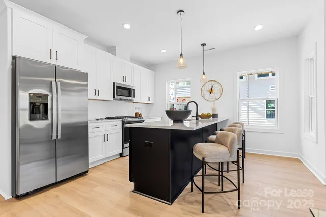 a kitchen with granite countertop a refrigerator a stove a sink dishwasher a dining table and chairs with wooden floor