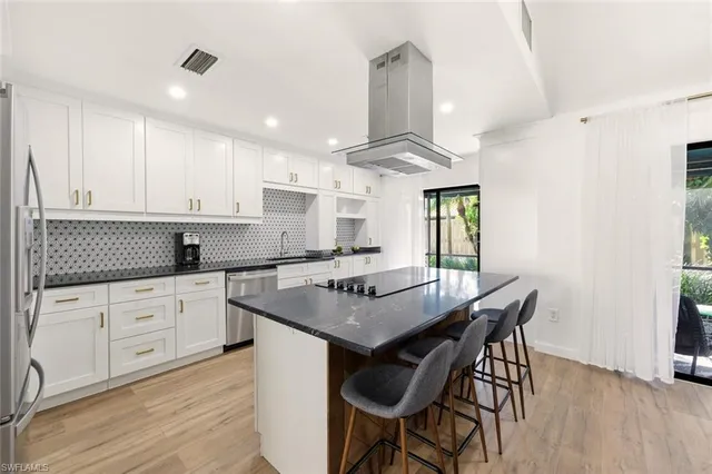 a kitchen with stainless steel appliances granite countertop a stove a refrigerator a sink a dining table and chairs with wooden floor