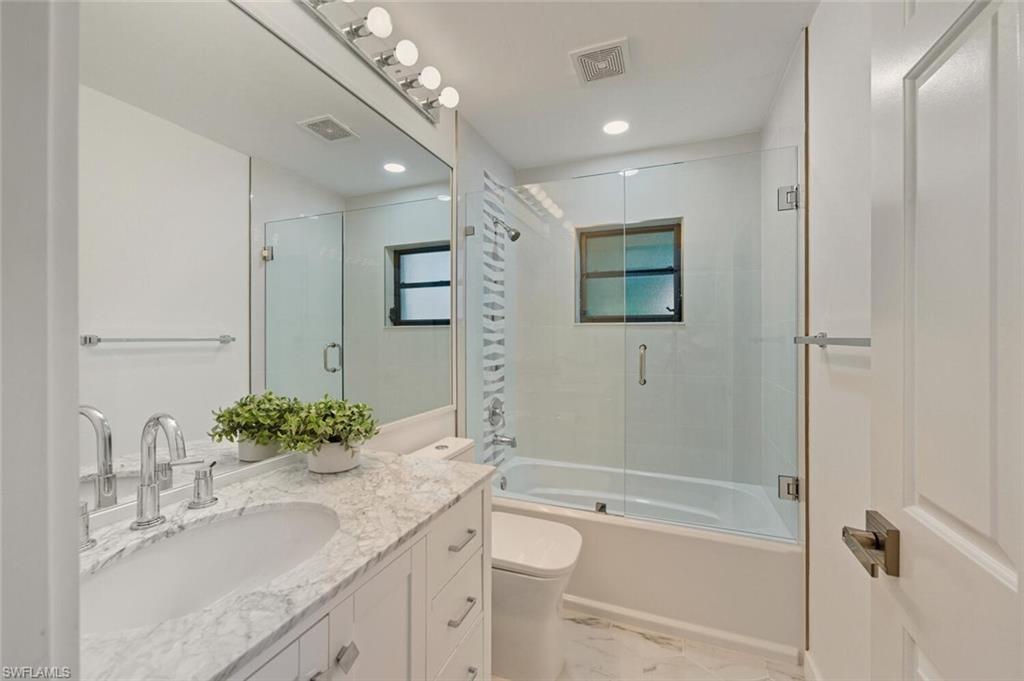 772 Reef Point Circle Naples, FL 34108 - Photo 20 of 46 a bathroom with a granite countertop sink a mirror a bathtub and shower