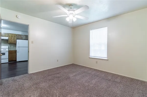 an empty room with chandelier fan and windows