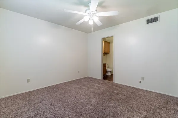 an empty room with a chandelier fan and windows