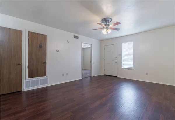 an empty room with wooden floor window and ceiling fan