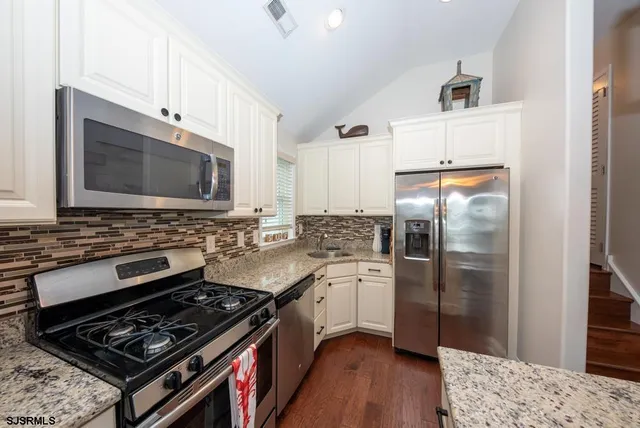 a kitchen with stainless steel appliances and wooden floor