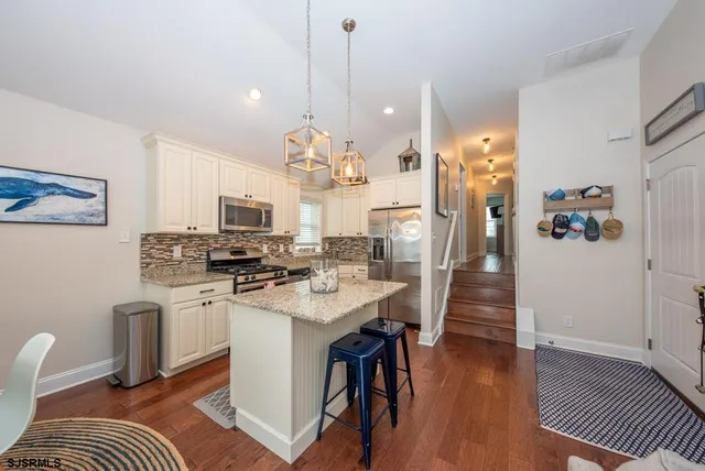a kitchen with stainless steel appliances kitchen island granite countertop a sink a stove and a wooden floors