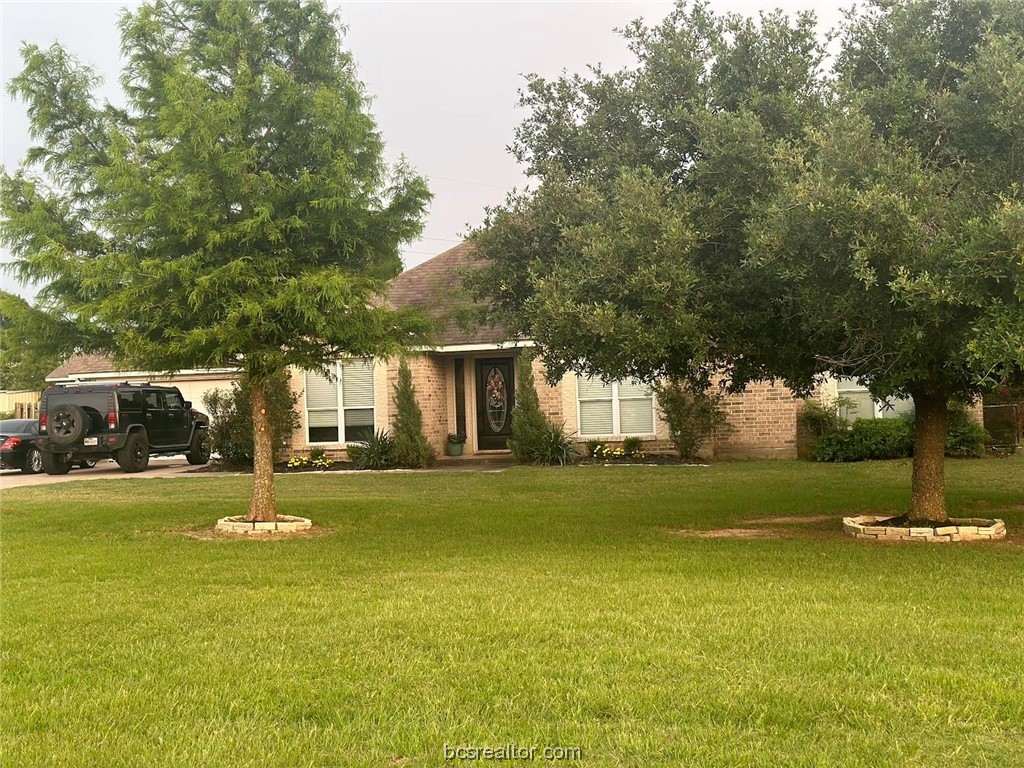 a view of a house with a big yard and large trees