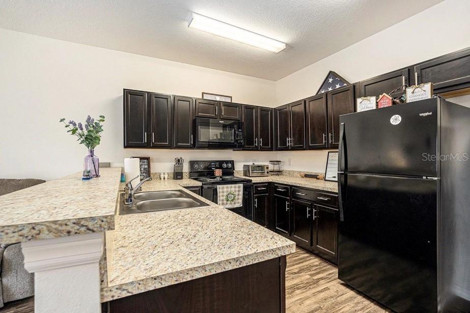 5521 Yellowfin Court New Port Richey, FL 34652 - Photo 8 of 23 a kitchen with kitchen island granite countertop a refrigerator stove microwave and sink