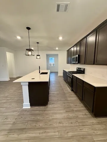 a large kitchen with stainless steel appliances kitchen island granite countertop a large counter top and wooden floors