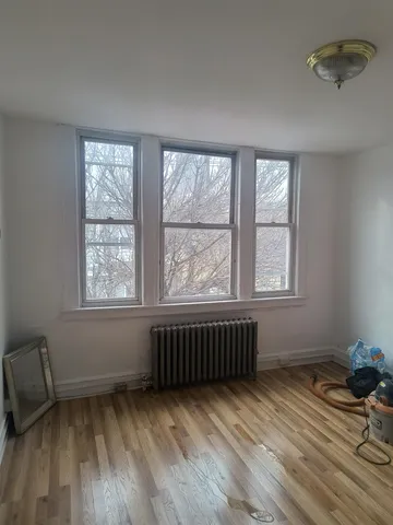 a view of an empty room with a window and wooden floor