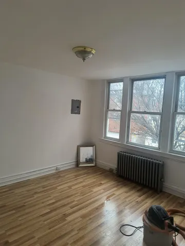 a view of an empty room with a window and wooden floor