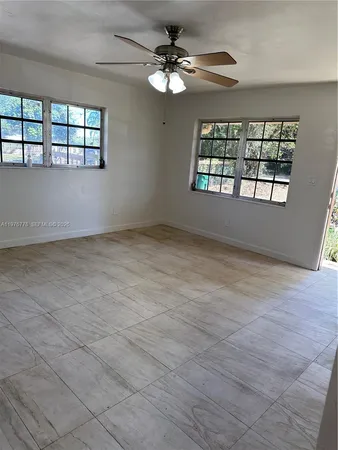an empty room with windows and ceiling fan