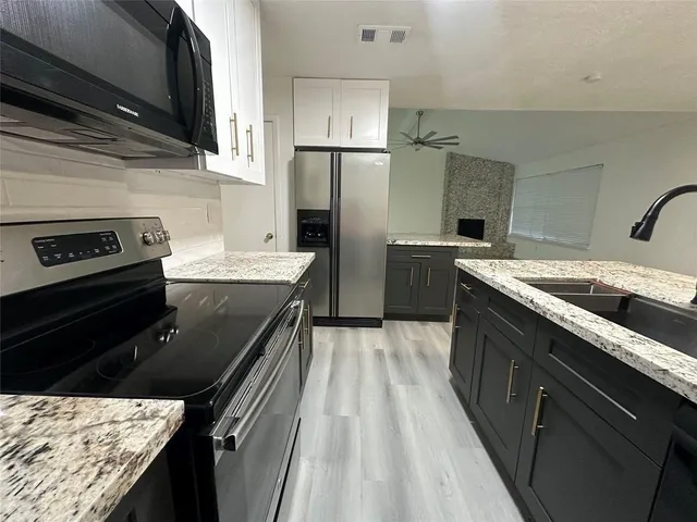 a kitchen with granite countertop stainless steel appliances a sink stove top oven and granite counter top