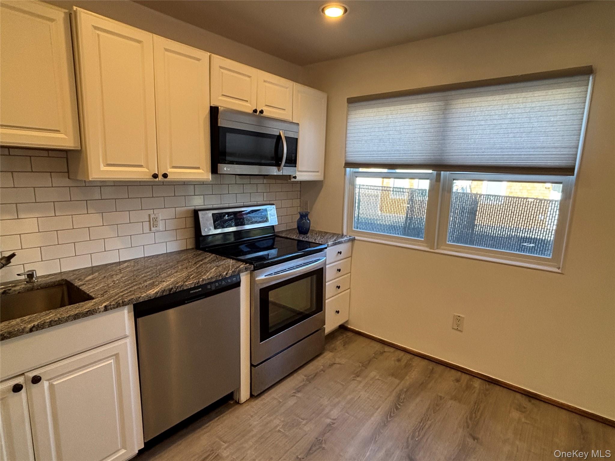 40 Canoe Place Road, Unit 4 Hampton Bays, NY 11946 - Photo 11 of 36 a kitchen with stainless steel appliances granite countertop white cabinets stove a sink and dishwasher